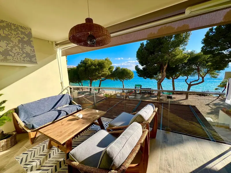 Espace de détente extérieur avec mobilier en bois et vue sur la mer.