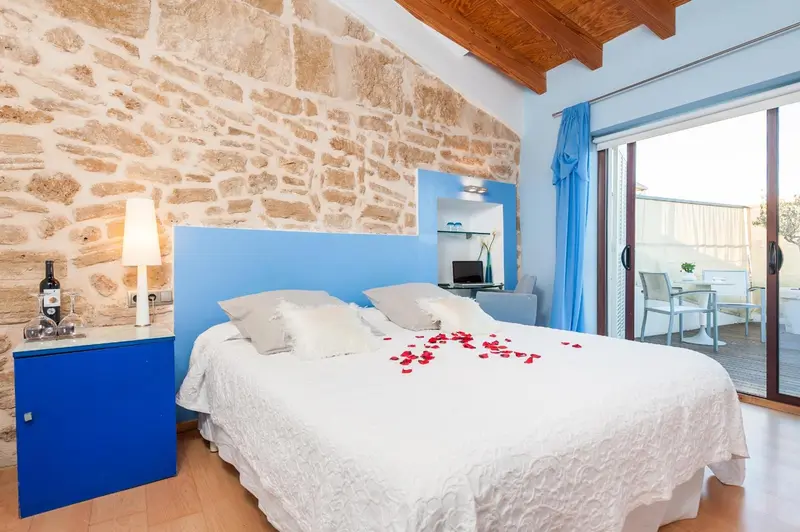 Une chambre lumineuse avec un grand lit décoré de pétales de fleurs.