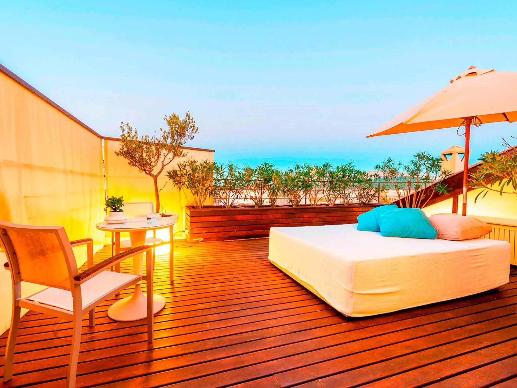 Terrasse aménagée avec salon de jardin et lit de repos face à la mer.