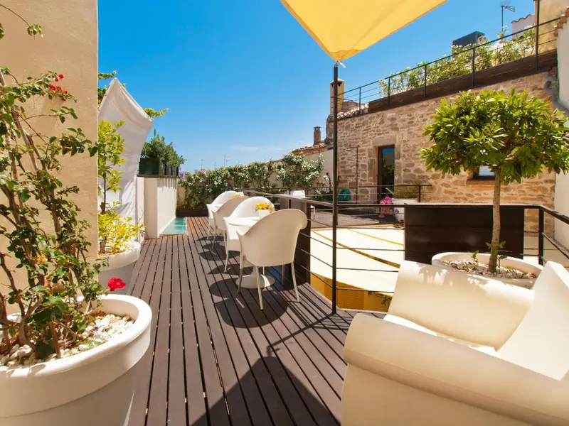 Terrasse aménagée avec mobilier blanc et végétation luxuriante.