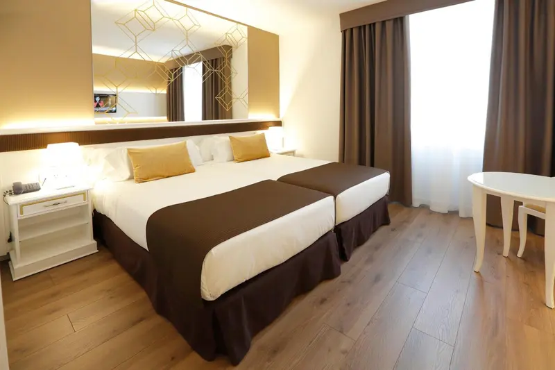 Chambre lumineuse avec un grand lit et un miroir décoratif.