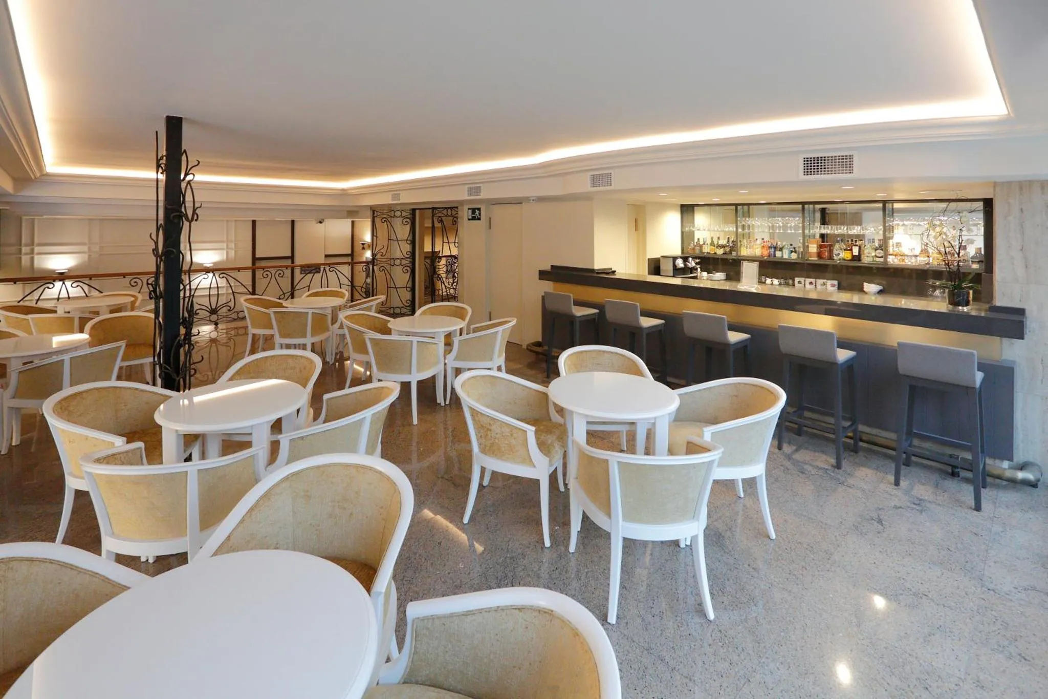 Une salle lumineuse avec des tables et des chaises, ainsi qu'un comptoir de bar.