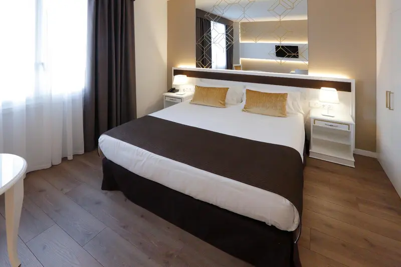 Une chambre lumineuse avec un grand lit recouvert d'une courtepointe.