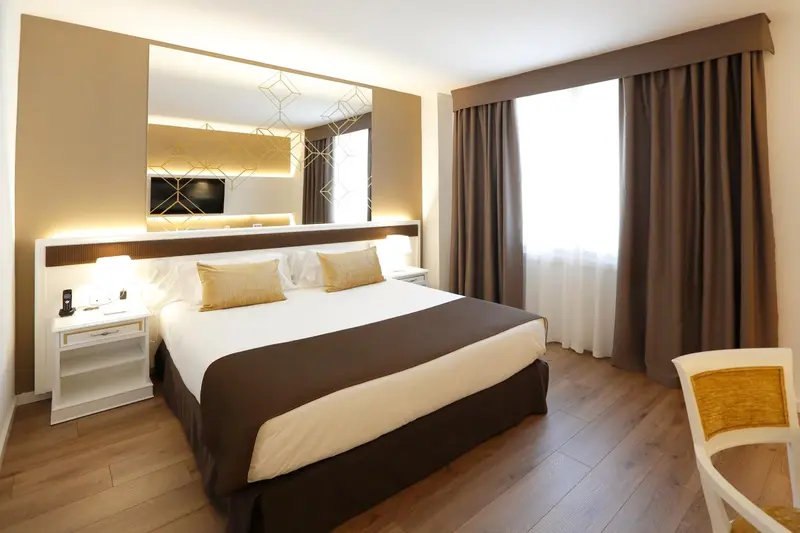 Une chambre lumineuse avec un grand lit et des meubles blancs.