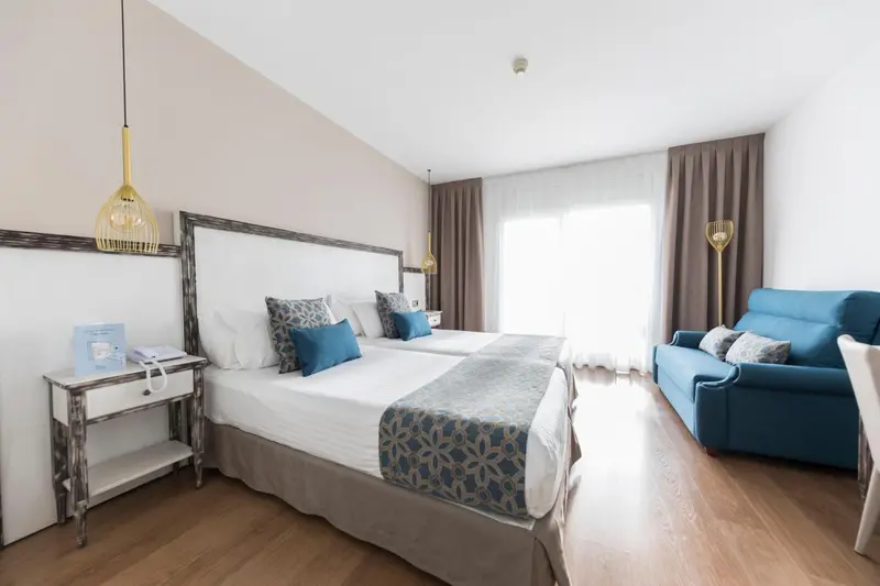 Une chambre lumineuse avec deux lits et un canapé bleu.