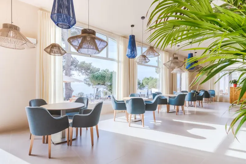 Une salle lumineuse avec des tables et des chaises près de grandes fenêtres.