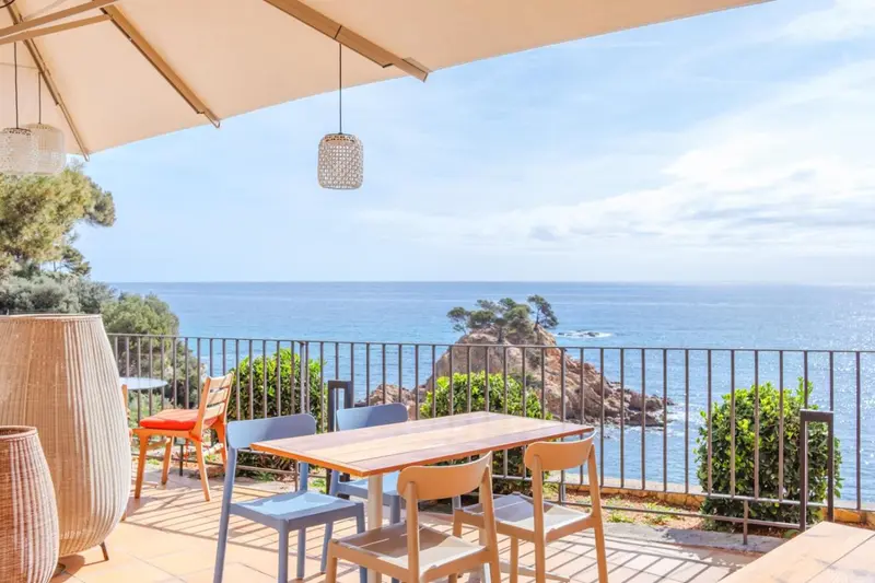 Terrasse avec table et chaises donnant sur la mer.