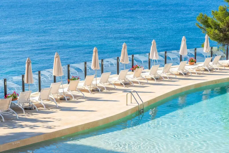 Terrasse avec transats et parasols au bord d'une piscine.