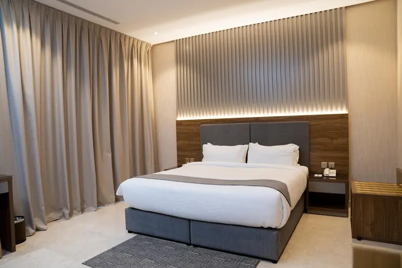 Une chambre avec un grand lit et des rideaux beiges.