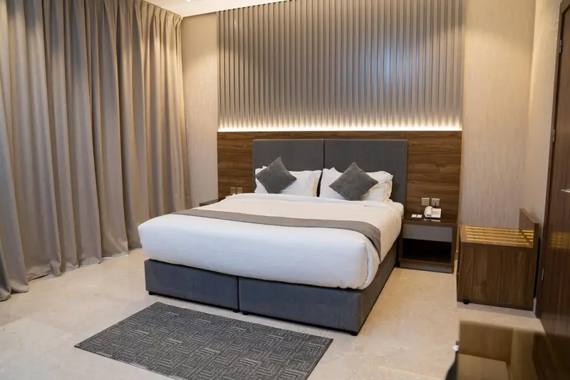 Une chambre d'hôtel moderne avec un grand lit et des rideaux beiges.