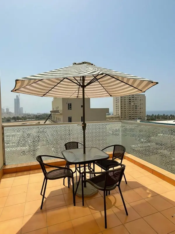 Une table et des chaises sont disposées sur une terrasse ensoleillée.