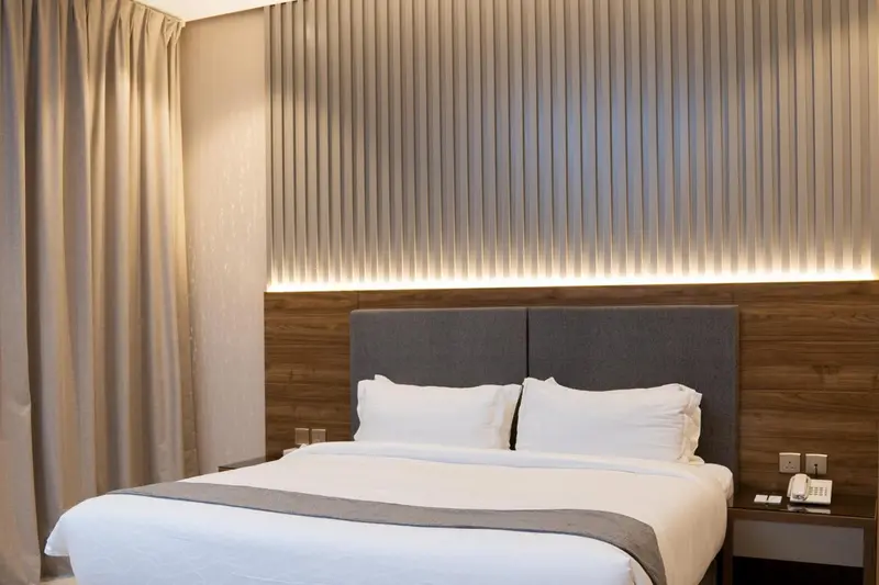 Un lit double avec des oreillers blancs dans une chambre décorée de rideaux et de panneaux muraux.
