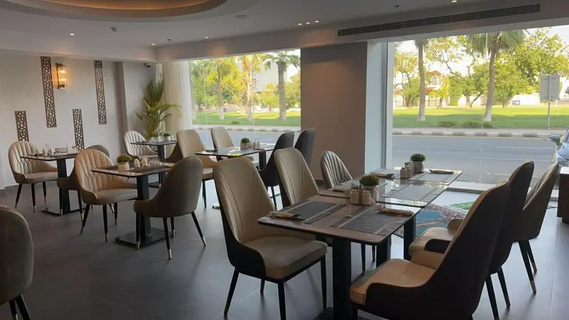 Une salle de restaurant lumineuse avec des tables dressées et de larges baies vitrées.