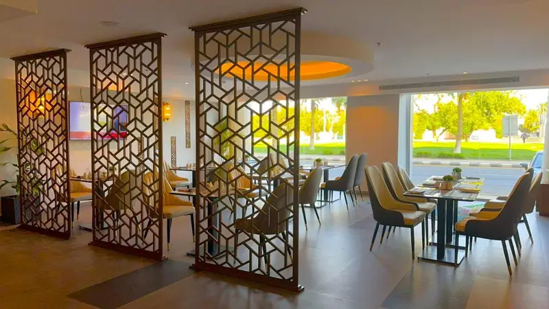 Une salle lumineuse avec des cloisons ajourées et des tables disposées pour les repas.
