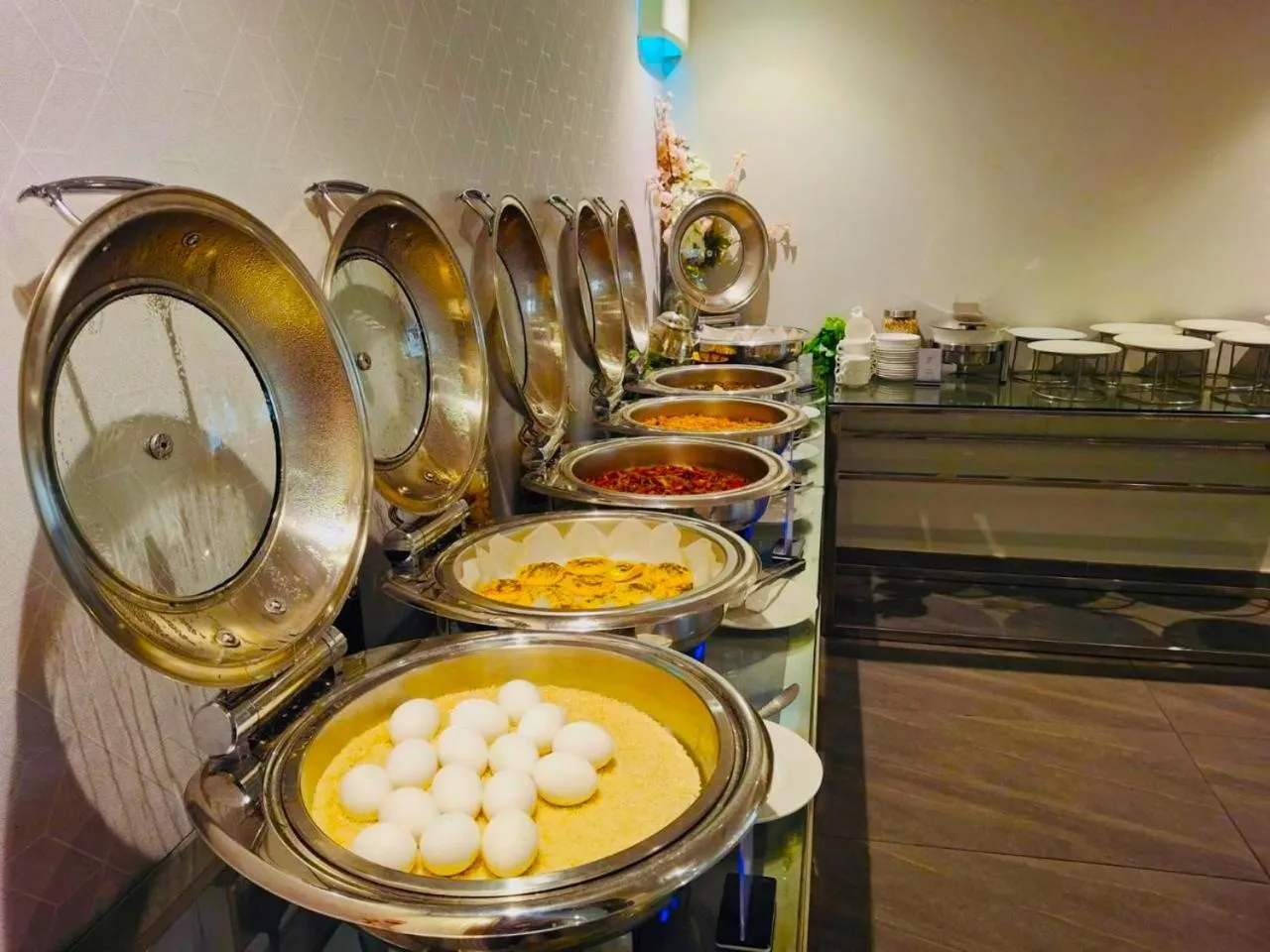 Un buffet propose une variété de plats chauds dans des récipients en métal.