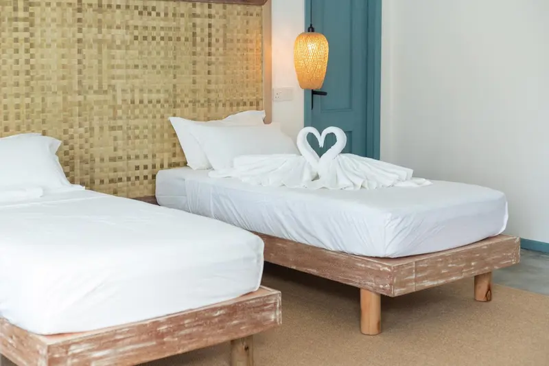 Lit préparé avec des serviettes en forme de cygnes dans une chambre lumineuse.