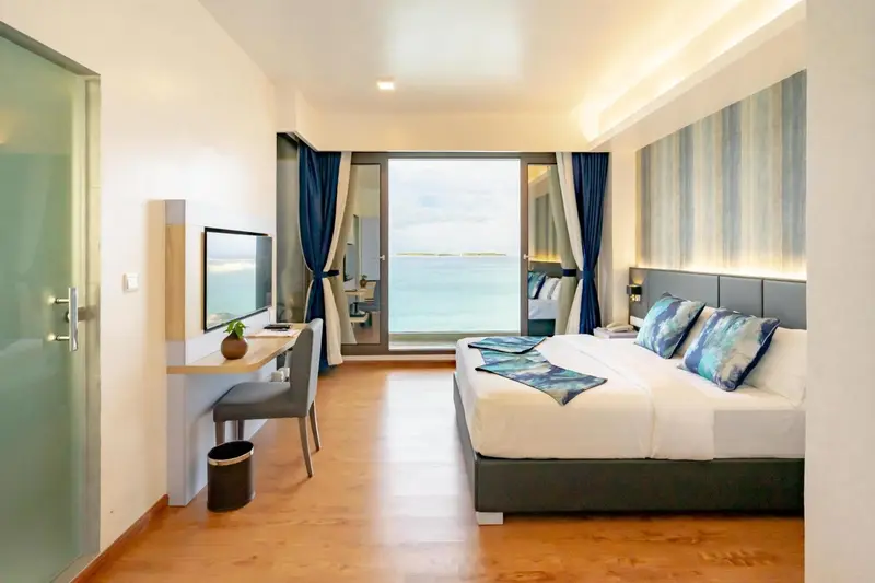 Chambre lumineuse avec un grand lit et vue sur la mer.