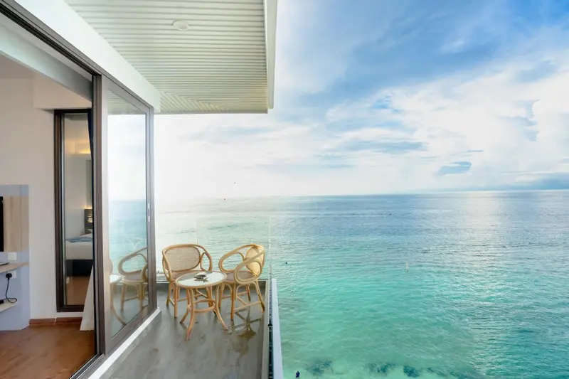 Vue sur la mer depuis une terrasse aménagée avec des fauteuils et une table.