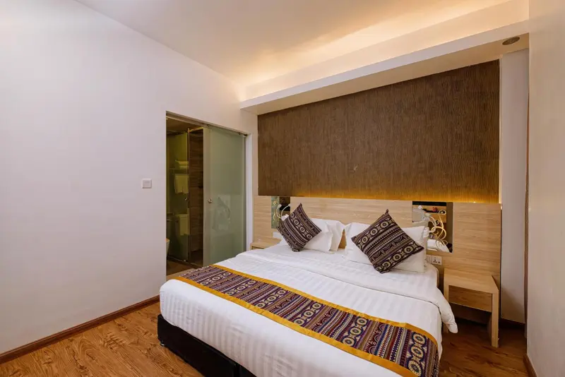 Une chambre lumineuse avec un grand lit recouvert d'une courtepointe décorative.