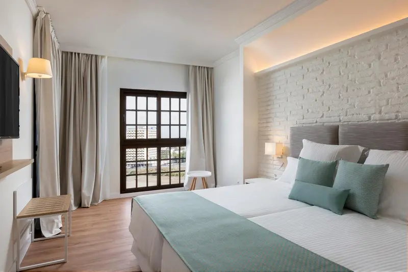 Une chambre lumineuse avec un grand lit et une fenêtre.