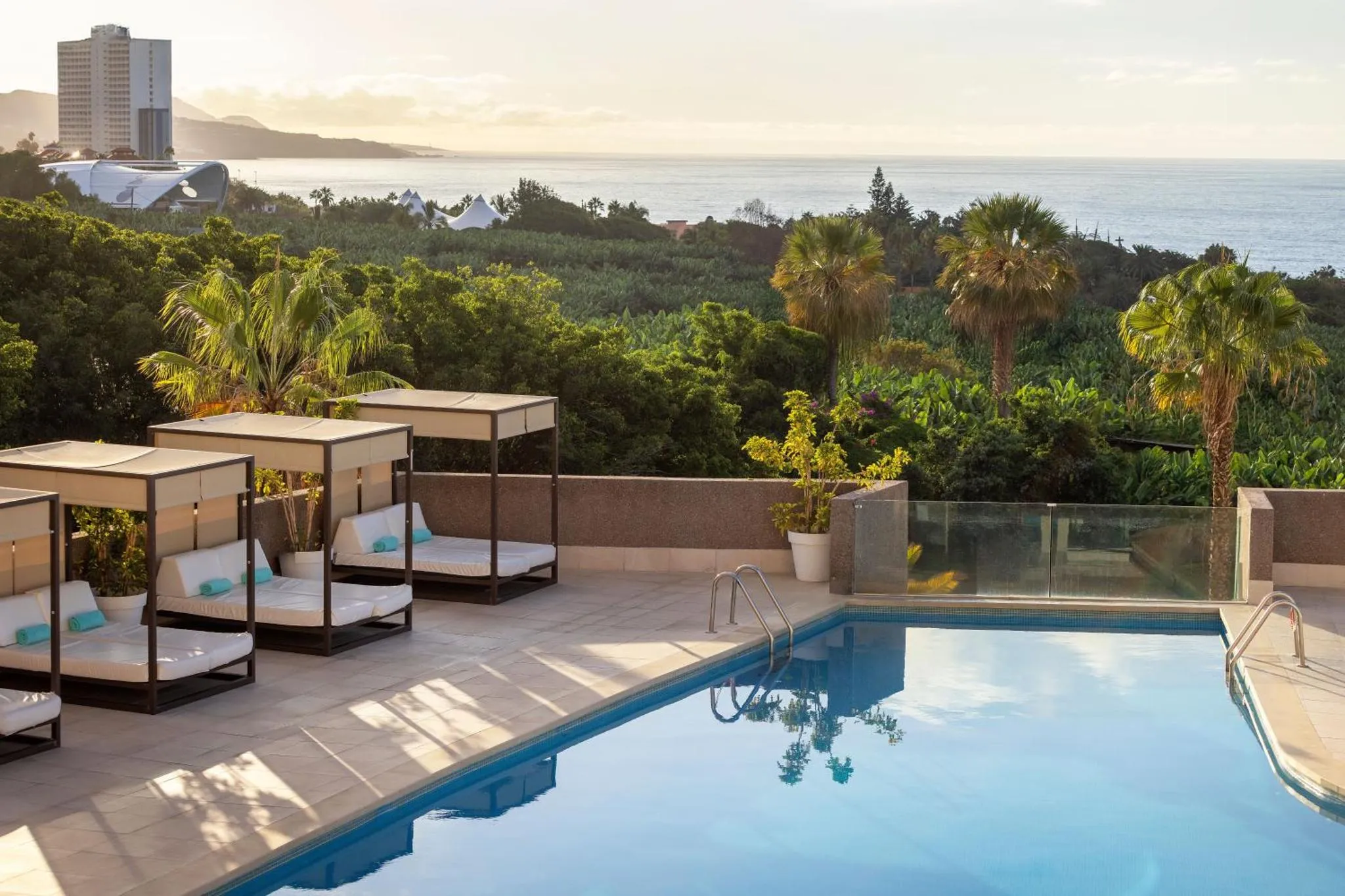 Terrasse avec transats et piscine au bord d'une vue sur la mer.