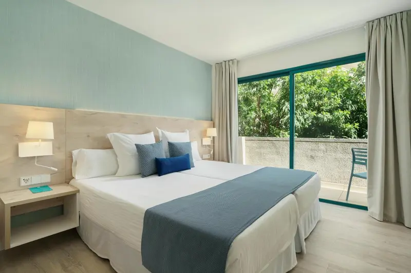 Une chambre lumineuse avec un grand lit et une baie vitrée.