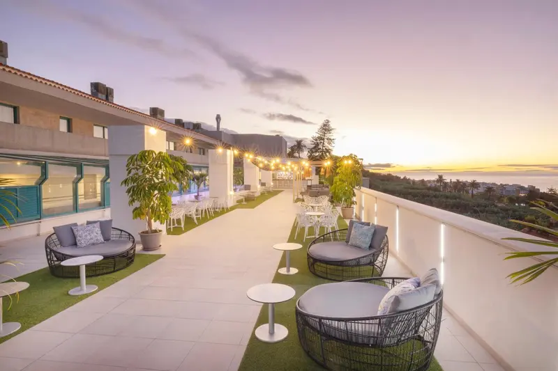 Terrasse aménagée avec des salons et une vue sur la mer au coucher du soleil.