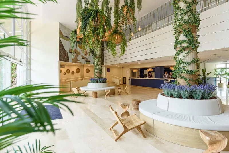 Vaste hall d'accueil décoré de plantes suspendues et de mobilier en bois clair.
