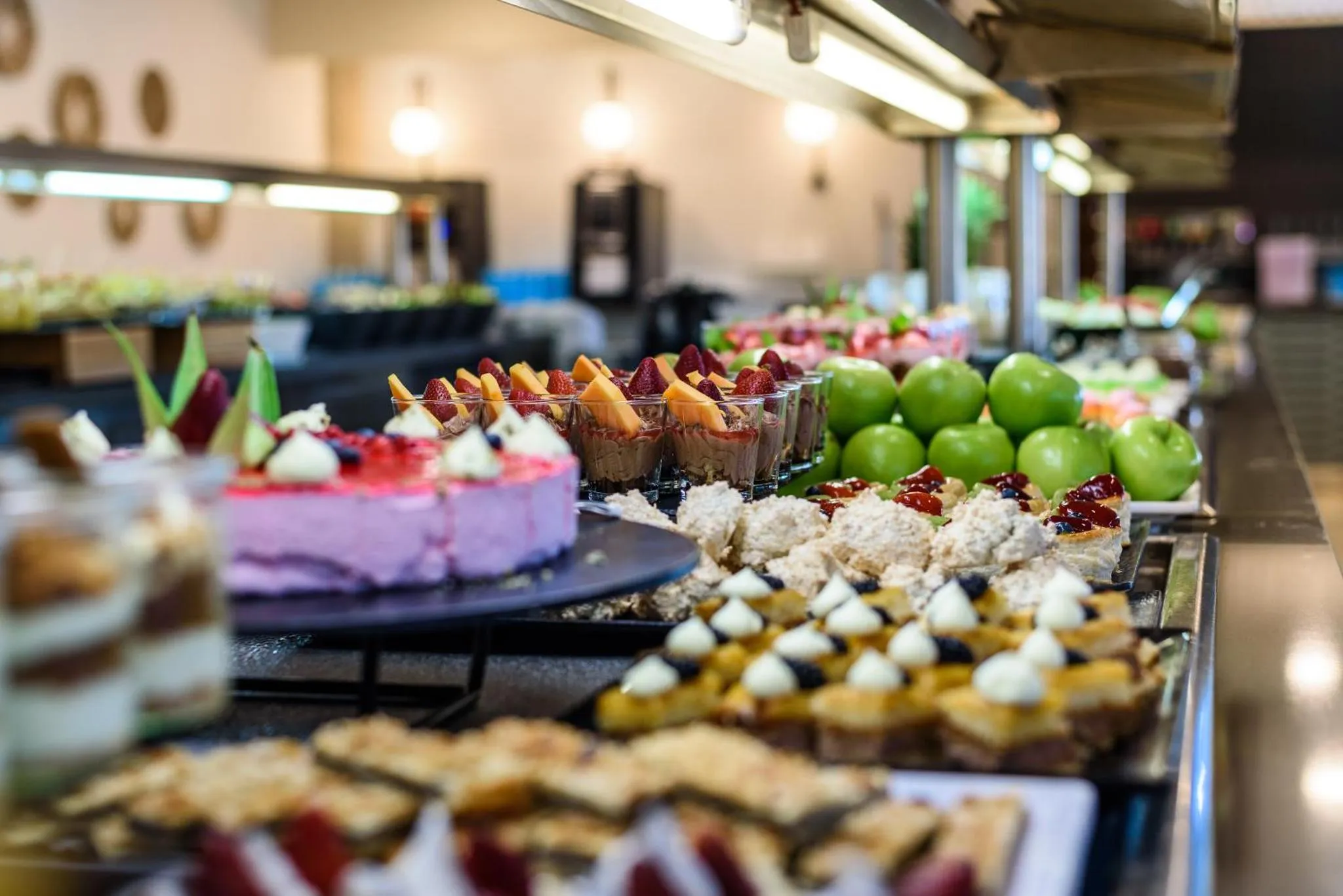 Un buffet propose une grande variété de desserts colorés et de fruits frais.