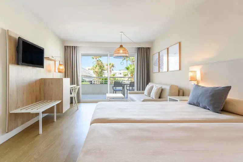 Une chambre lumineuse avec un lit et un coin salon donnant sur une terrasse.