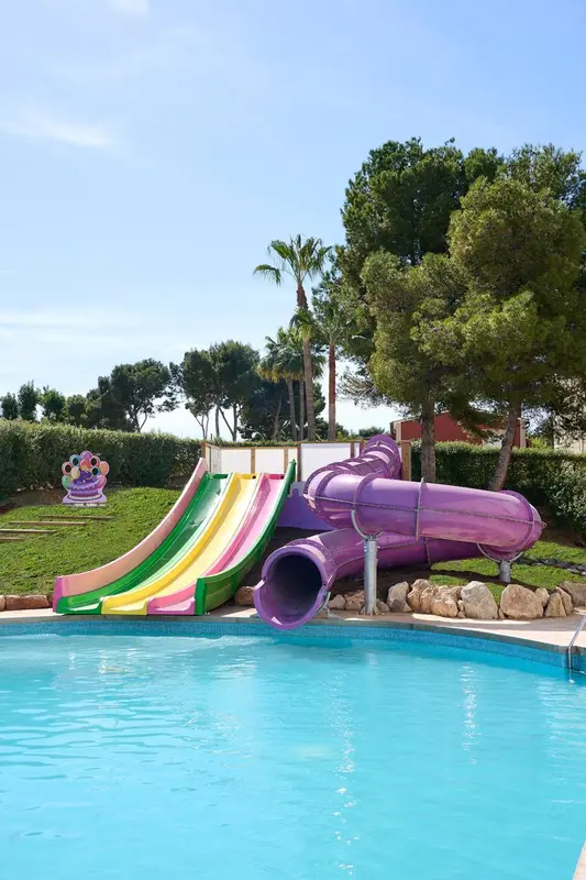 Toboggans colorés au bord d'une piscine ensoleillée.