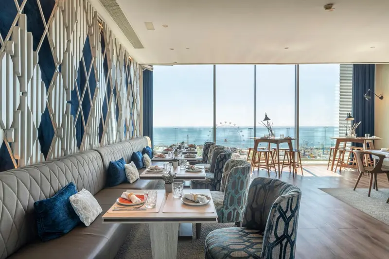 Une salle à manger lumineuse avec de grandes baies vitrées donnant sur la mer.