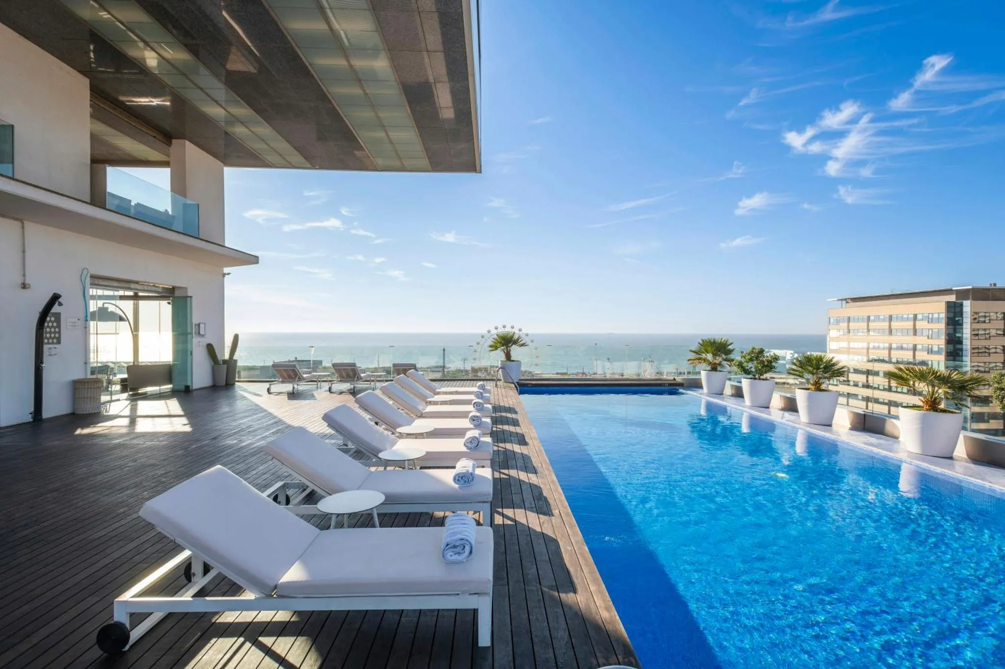 Transats blancs alignés au bord d'une piscine à débordement avec vue sur la mer.