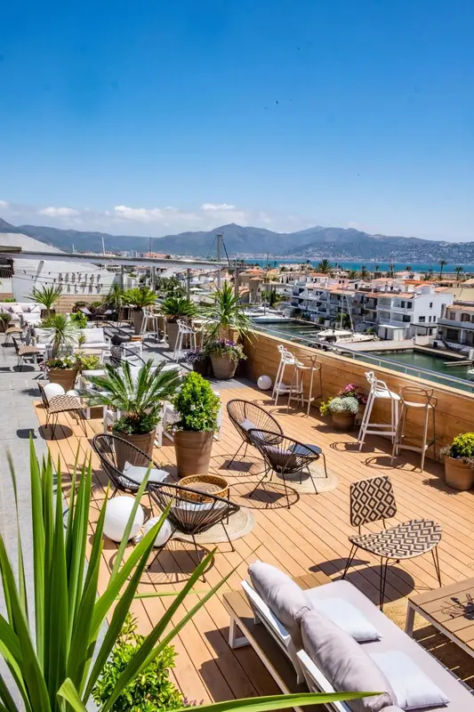 Terrasse aménagée avec mobilier de jardin et vue sur la mer et la ville.