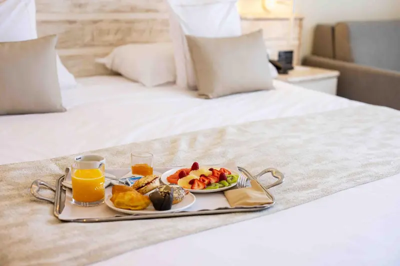Un petit-déjeuner est servi sur un plateau posé sur un lit préparé.