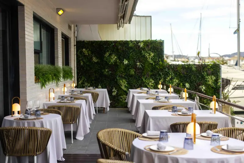 Une terrasse de restaurant avec des tables dressées en extérieur.