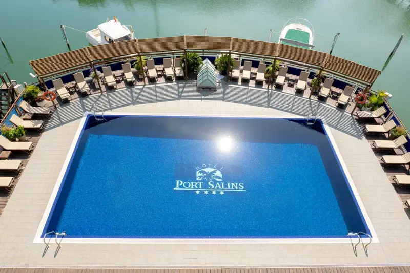 Vue aérienne d'une piscine d'hôtel avec des transats et un accès à la mer.