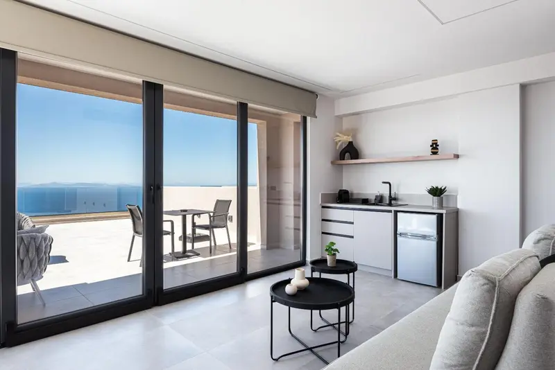 Espace de vie lumineux avec cuisine équipée et vue sur la mer depuis une terrasse.