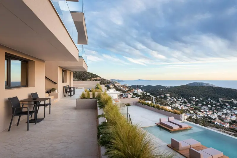 Terrasse avec mobilier d'extérieur donnant sur une piscine et un paysage côtier.