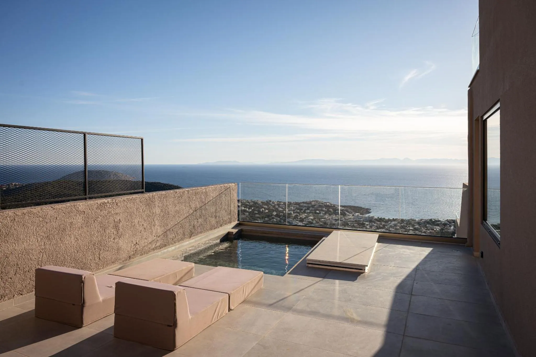 Terrasse avec transats et petite piscine offrant une vue sur la mer.