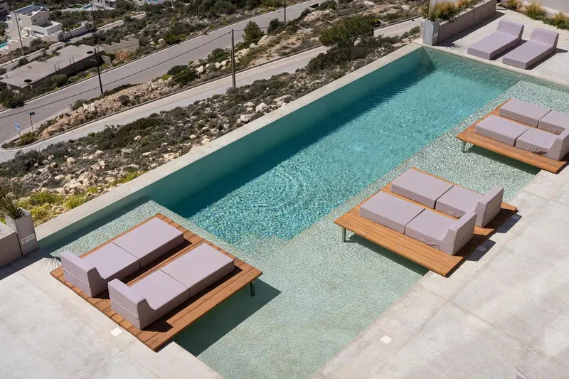 Vue aérienne d'une piscine rectangulaire entourée de transats.