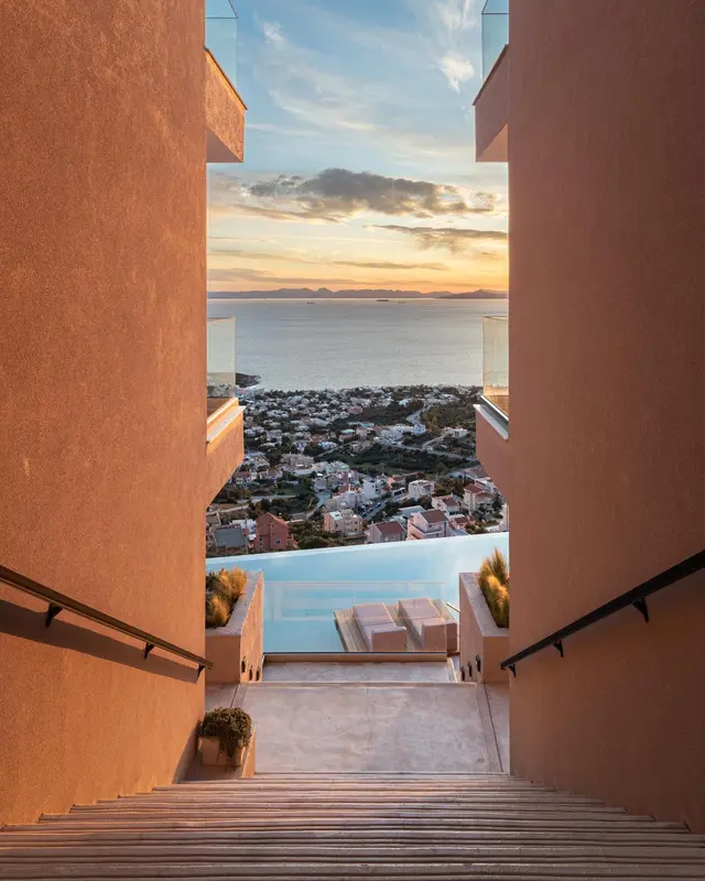 Vue sur la mer et la ville depuis un escalier menant à une piscine.