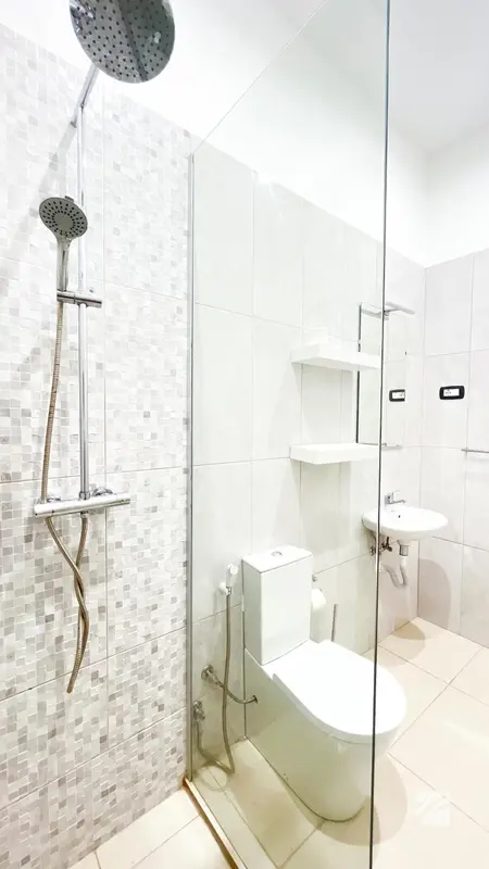 Une douche à l'italienne moderne avec carrelage gris et équipements sanitaires blancs.