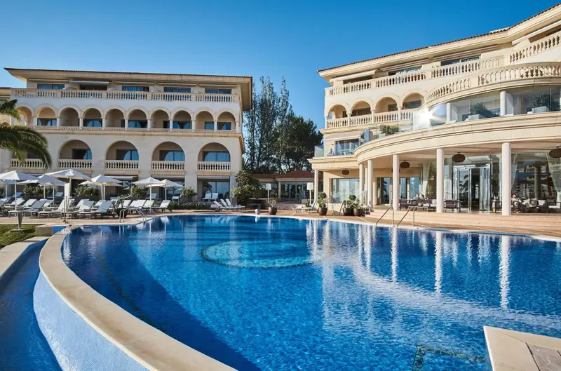 Vue d'une piscine devant un bâtiment beige à plusieurs étages.