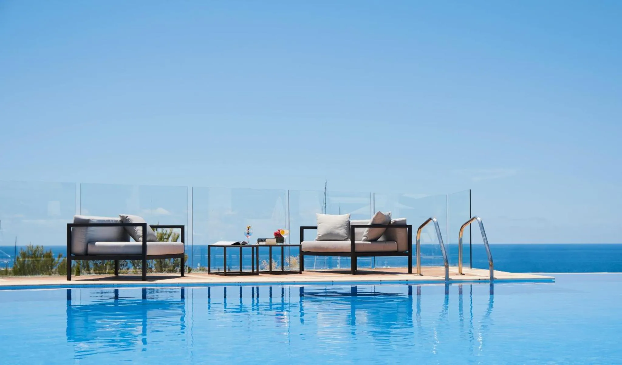 Mobilier de détente au bord d'une piscine à débordement avec vue sur la mer.