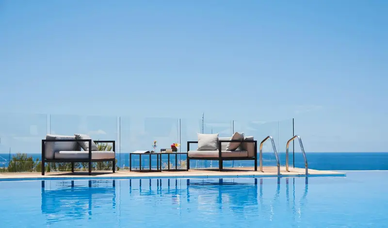 Mobilier de détente au bord d'une piscine à débordement avec vue sur la mer.