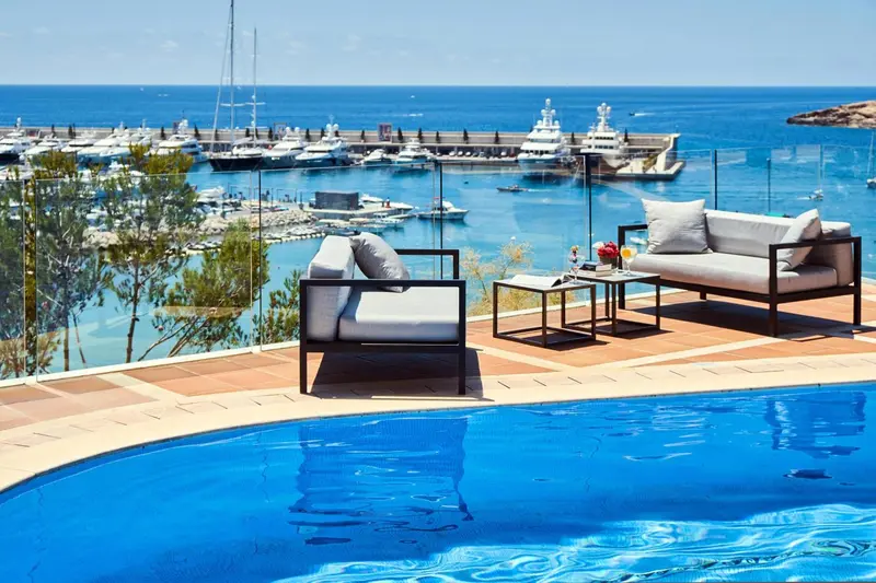 Terrasse avec mobilier d'extérieur et piscine donnant sur un port de plaisance.