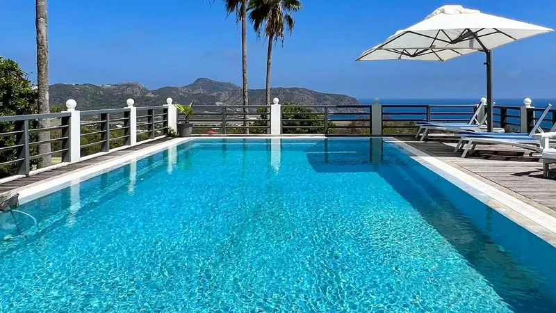 Une piscine rectangulaire avec une vue sur la mer et des montagnes.