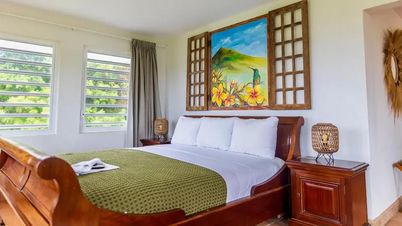 Une chambre lumineuse avec un grand lit à baldaquin et une décoration murale colorée.
