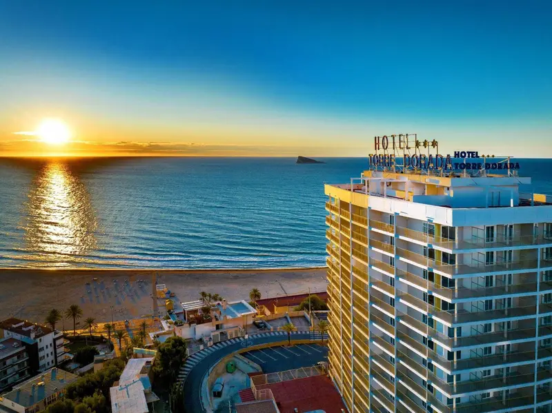 Vue aérienne d'un bâtiment moderne au bord de la mer au coucher du soleil.